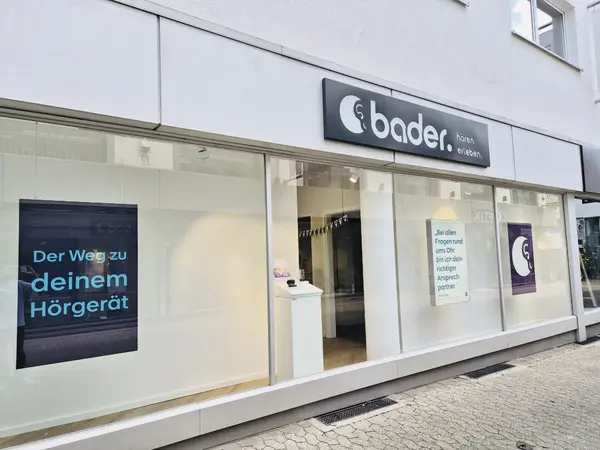 Schaufenster eines Hörakustiker-Geschäfts mit bader-Schild und Hörgeräte-Poster