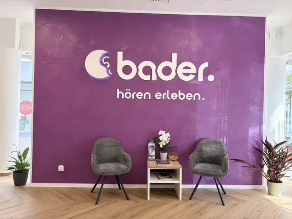 Wartebereich im Hörakustikgeschäft mit bader-Logo, zwei Stühlen und Tisch.